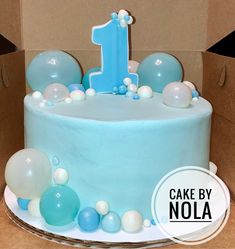 a birthday cake with blue frosting and balloons on the top is in a box