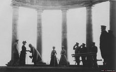 an old black and white photo of people standing in front of columns