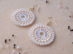 White and gold beaded circle drop earrings. These lovely statement earrings are made of quality Japanese and Czech glass beads and gold plated stainless steel components, using bead weaving technique. Earring hooks are made of hypoallergenic gold plated stainless steel.  Dimensions: width: 3.2 cm (1.3 in)                                               total length incl. hooks: 5 cm (2 in) These elegant earrings would make a lovely gift.  They will arrive wrapped in tissue paper in a padded envelope.  To see more earrings I have made, please have a look here: https://www.etsy.com/shop/SaffronWell?ref=dashboard-header Estimated DELIVERY times: UK - 3-5 days USA - 7-14 days Canada - 7-21 days France - 7-14 days  International orders will be shipped via Royal Mail International Tracked. Please Beaded Pearl Round Earrings, White Beaded Round Earrings For Party, Beaded Round Pearl Earrings, White Beaded Earrings With Pearl Drop, White Beaded Round Earrings With Ear Wire, White Round Beaded Earrings With Pearl Drop, White Beaded Earrings With Ear Wire, Festive Jewellery, Beaded Circle