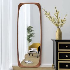 a large mirror sitting on top of a dresser next to a vase filled with flowers