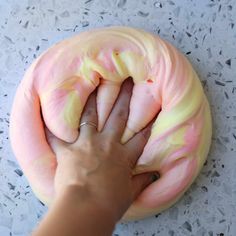 a person holding a doughnut with pink and yellow frosting on it