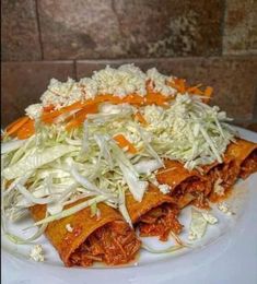 shredded cabbage and carrots are piled on top of tortilla shells with cheese