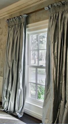 the curtains are pulled back in front of the window with drapes on each side