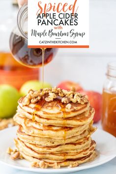 a stack of pancakes with maple syrup being drizzled over them on a white plate