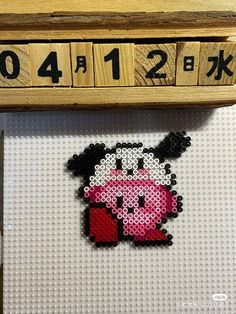 a cross stitch picture with numbers on it and a pink pig in the middle is hanging from a wooden frame