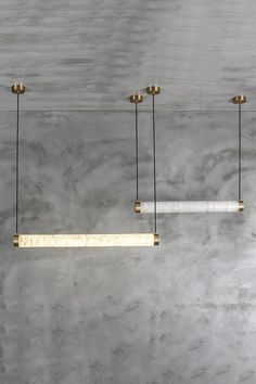 three light fixtures hanging from the ceiling in a room with concrete walls and flooring