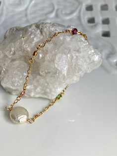 "Introducing a beautiful gem laden 14k gold filled chain with a blue sapphire, pink quartz, orange topaz, peridot, and amethyst.  Focal bead a highly iridescent, 12mm coin pearl.  The S clasp makes this bracelet adjustable from 7 1/2 to 7 3/4\". However this can be customer sized.  14k gold filled lobster clasp is new and like all the metal components manufactured in the USA to assure quality and meet EU Standards of gold quality. Handmade at my bench in Boston." 14k Gold Filled Jewelry With Gemstone Accents, Gold Sterling Silver Round Pearl Bracelet, Gold-colored Sterling Silver Pearl Bracelet, Gold Colored Sterling Silver Round Pearl Bracelet, Gold-toned Sterling Silver Round Pearl Bracelet, Elegant 14k Gold-filled Jewelry With Gemstone Accents, Gold Pearl Birthstone Jewelry, Gold Faceted Pearl Jewelry, Faceted Pearl Jewelry In Gold