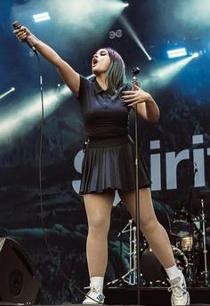 a woman standing on top of a stage with her arms in the air and holding a microphone