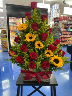 a bouquet of roses and sunflowers in a basket on a table at a store