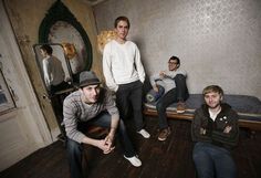 four young men sitting in a small room