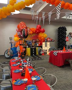 a room filled with lots of balloons and tables covered in red, orange and yellow decorations