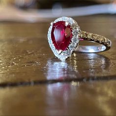 a close up of a ring with a red stone in it on a wooden table