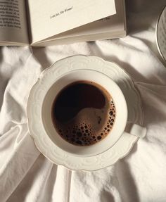 a cup of coffee sitting on top of a saucer next to an open book