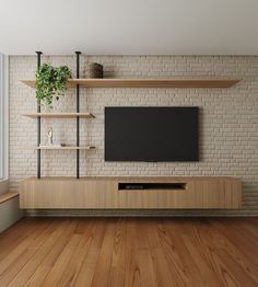 a tv is mounted on a brick wall in a room with wooden floors and shelves