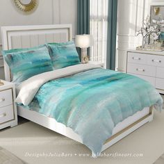 a bed with blue and white comforters in a bedroom next to a dresser, mirror and lamp