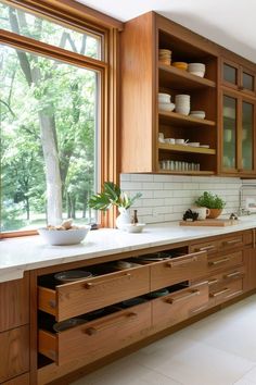 a kitchen filled with lots of wooden cabinets and counter top space next to a window