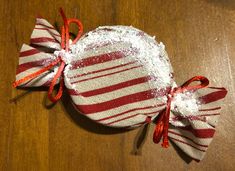 a red and white striped bag with sequins on it sitting on a wooden table