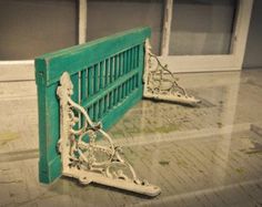 a green gate sitting on top of a wooden floor next to a window with white trim