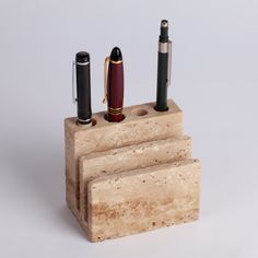 a pen holder with three pens and two lighters in it on a white background