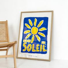 there is a chair next to a painting that says soleil on it and a wooden frame