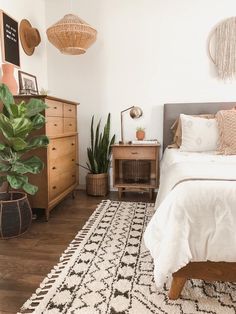 a bed room with a neatly made bed and lots of plants on the side tables