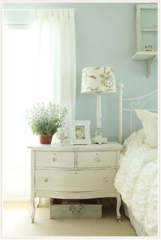 a white bed sitting next to a window in a bedroom under a light blue wall