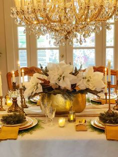 a dining room table set with candles and flowers in a gold vase on it's centerpiece