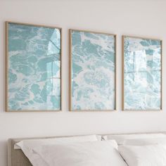 three paintings hang on the wall above a bed