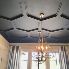 a chandelier hanging from the ceiling in a room with blue walls and curtains