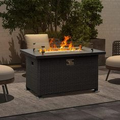 a fire pit sitting on top of a patio next to two chairs and a table