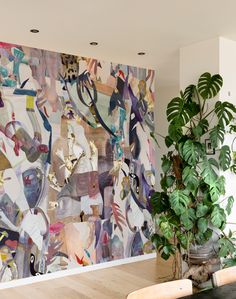 a large painting on the wall next to a potted plant in a living room