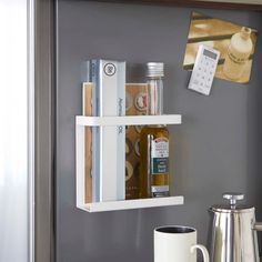 a shelf that has some books and other items on it next to a coffee pot