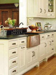 a kitchen with white cabinets and black counter tops