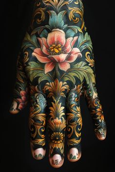 a person's hand covered in tattoos with flowers and leaves on the inside of it