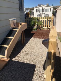 a wooden bench sitting in the middle of a gravel covered yard next to a house