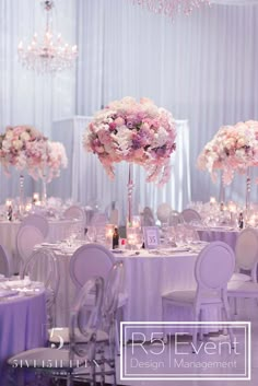 an elegant wedding reception with purple and white flowers in tall centerpieces at the head table