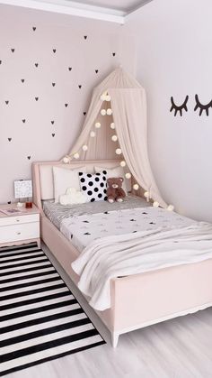 a bedroom with pink walls and black and white accessories on the bed, along with an area rug