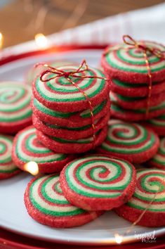 red, green and white cookies are stacked on a plate with twine ribbons tied around them