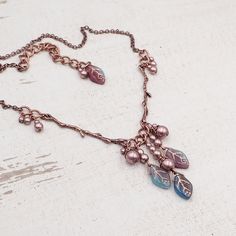 "This handmade necklace features beautifully detailed antiqued copper branches paired with clusters of limited-edition artisan Czech glass leaf beads. Each bead is a swirly mix of transparent purple, transparent teal, and opaque aqua blue glass with a metallic copper wash in the veins of the beads. I finished the clusters with metallic Czech glass faux pearl beads. --------------------------------------------------------------------------------------------- Dimensions and details: - The drop of Cheap Elegant Czech Glass Necklaces, Cheap Handmade Czech Glass Necklaces, Cheap Czech Glass Necklaces With Polished Beads, Luxury Czech Glass Necklaces For Gifts, Luxury Elegant Czech Glass Necklaces, Cheap Adjustable Czech Glass Necklaces, Luxury Elegant Necklace With Czech Glass, Cheap Handmade Czech Glass Beaded Necklaces, Luxury Czech Glass Beaded Necklace