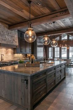 a large kitchen with an island in the middle and lights hanging from it's ceiling