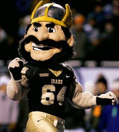 a mascot dressed in black and gold running on the field