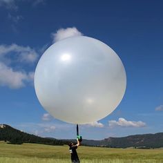 a person holding a large white balloon in the air