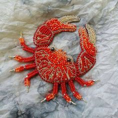 a red beaded crab brooch with gold accents