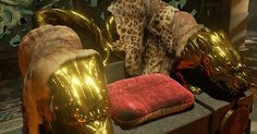 two gold and red animal heads sitting on top of a wooden bench next to a fire place