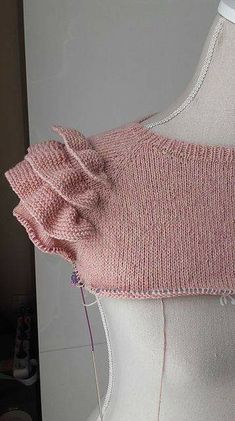 a close up of a mannequin wearing a pink sweater with ruffles