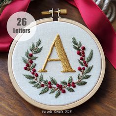 the letter a is surrounded by holly wreaths and red berries on a wooden table