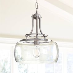 a light fixture hanging from the ceiling in a room with white walls and large windows