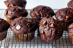 several chocolate muffins on a cooling rack with nuts and chocolate chips in them