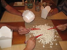 people are making marshmallows with chopsticks on a table