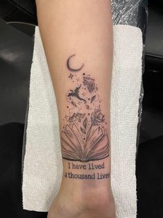 a person with a book tattoo on their arm that says i have lived a thousand lives